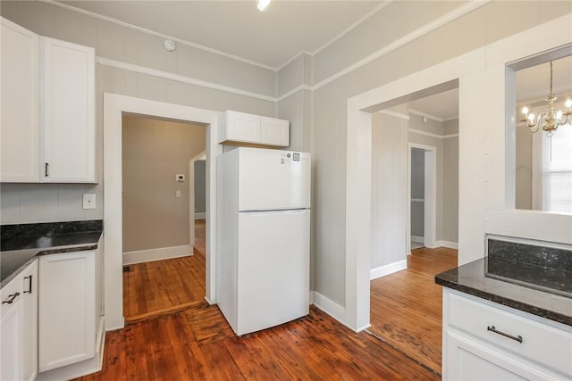kitchen with white cabinetry, ornamental molding, freestanding refrigerator, and dark wood finished floors