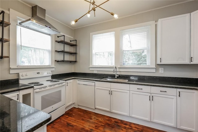 kitchen featuring white cabinets, wall chimney exhaust hood, a sink, ornamental molding, and white appliances