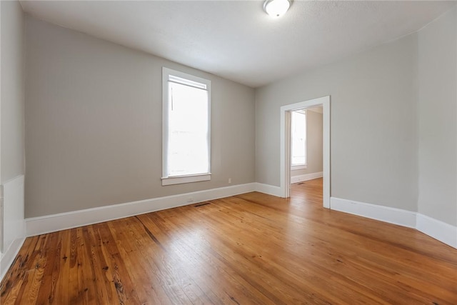 spare room featuring visible vents, light wood-style flooring, and baseboards