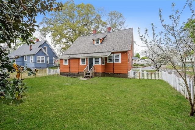 rear view of property featuring entry steps, a chimney, a fenced backyard, and a lawn