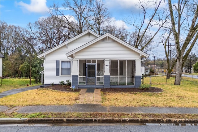 bungalow-style house featuring fence, a sunroom, and a front lawn