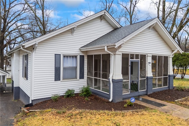 exterior space featuring a sunroom and roof with shingles