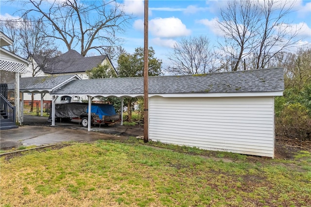 view of property exterior featuring an outbuilding, a shingled roof, driveway, and a lawn