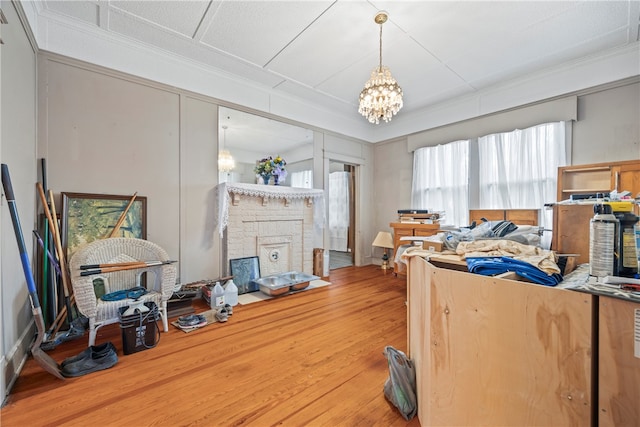 interior space with ornamental molding, a chandelier, wood finished floors, and a fireplace with flush hearth