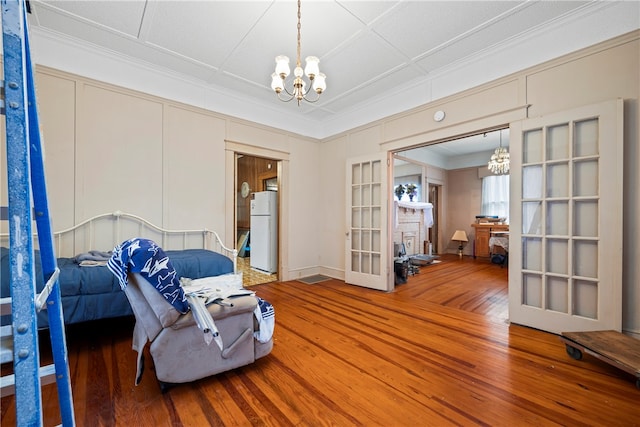 interior space featuring crown molding, wood-type flooring, a chandelier, and french doors