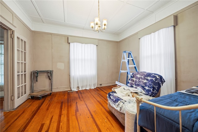 bedroom featuring crown molding, wood-type flooring, and a chandelier