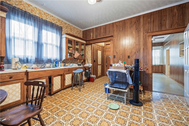 kitchen featuring ornamental molding, light countertops, wood walls, brown cabinets, and light floors