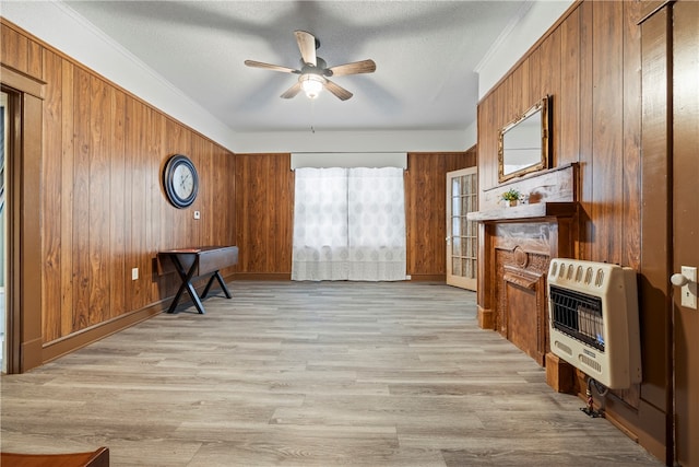 sitting room featuring light wood-style flooring, ceiling fan, wooden walls, and heating unit