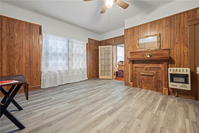 interior space featuring crown molding, ceiling fan, light wood-type flooring, and heating unit