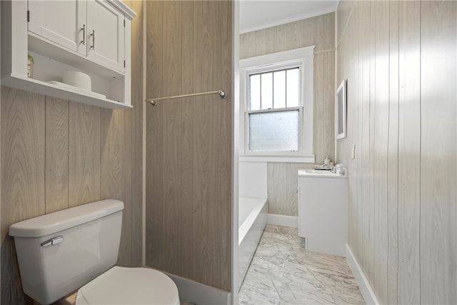 full bath with baseboards, toilet, wooden walls, a tub to relax in, and marble finish floor