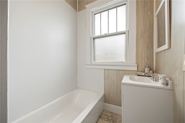 full bath featuring vanity, a tub, marble finish floor, and baseboards