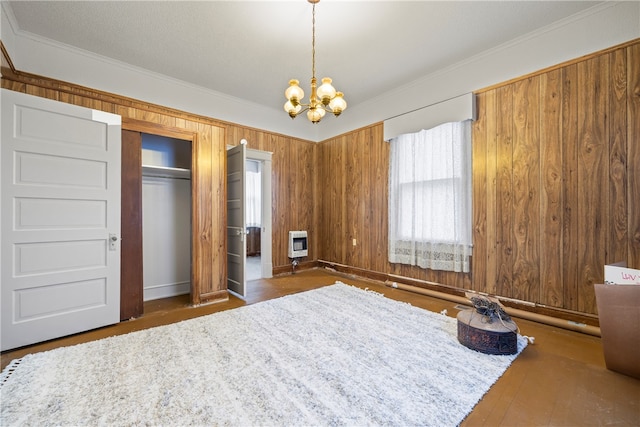 bedroom featuring a chandelier, wood finished floors, ornamental molding, and heating unit