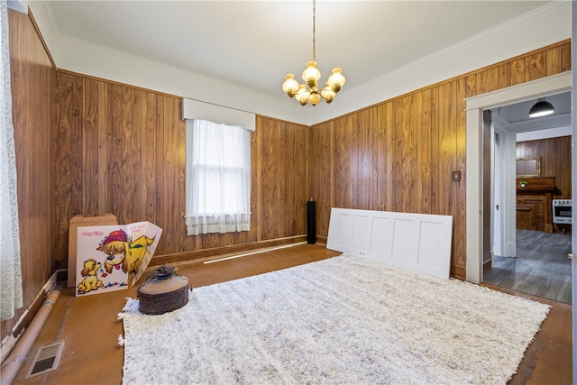 interior space with crown molding, visible vents, wood walls, baseboards, and a notable chandelier