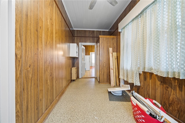 hallway with ornamental molding, wood walls, and baseboards