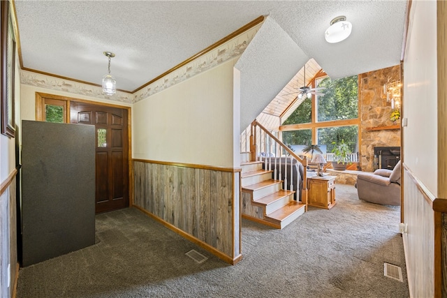 interior space with a textured ceiling, wooden walls, wainscoting, and visible vents