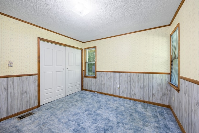 unfurnished bedroom with visible vents, a textured ceiling, and crown molding