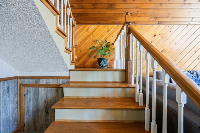 staircase with wood walls and wood finished floors