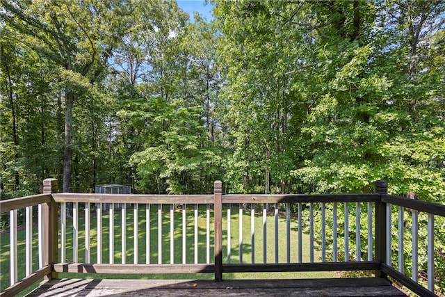wooden deck featuring a shed, an outdoor structure, and a lawn