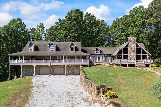 view of front of home with a deck, stone siding, a garage, a front lawn, and gravel driveway