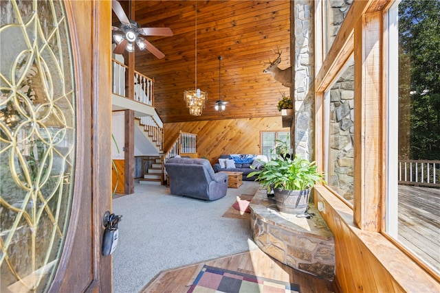 interior space featuring a wealth of natural light, wooden walls, high vaulted ceiling, and ceiling fan with notable chandelier