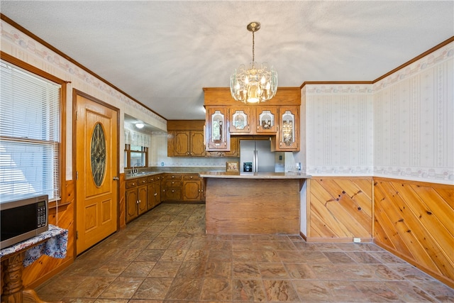 kitchen featuring stainless steel appliances, a notable chandelier, brown cabinets, and ornamental molding
