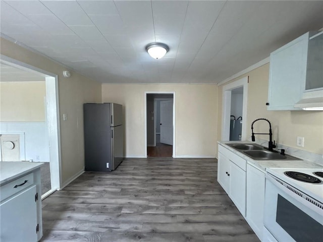 kitchen featuring white electric range oven, freestanding refrigerator, white cabinets, wood finished floors, and a sink