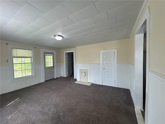 unfurnished living room featuring wainscoting and carpet