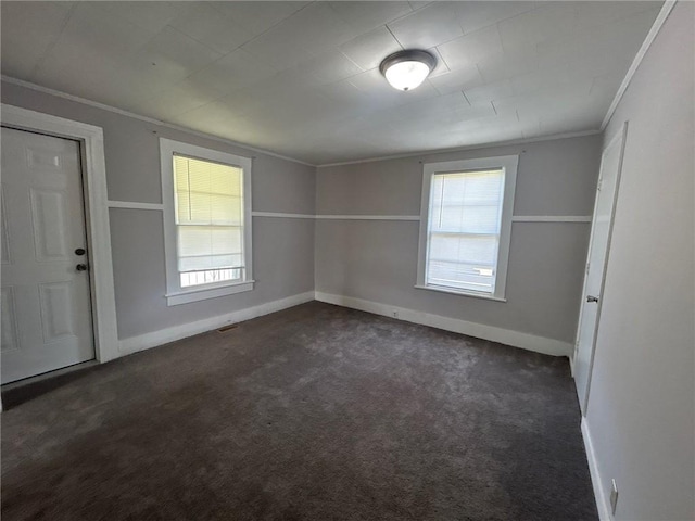 unfurnished room with plenty of natural light, baseboards, dark carpet, and crown molding