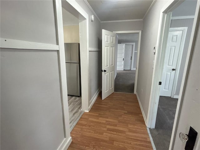 corridor with baseboards, crown molding, and wood finished floors