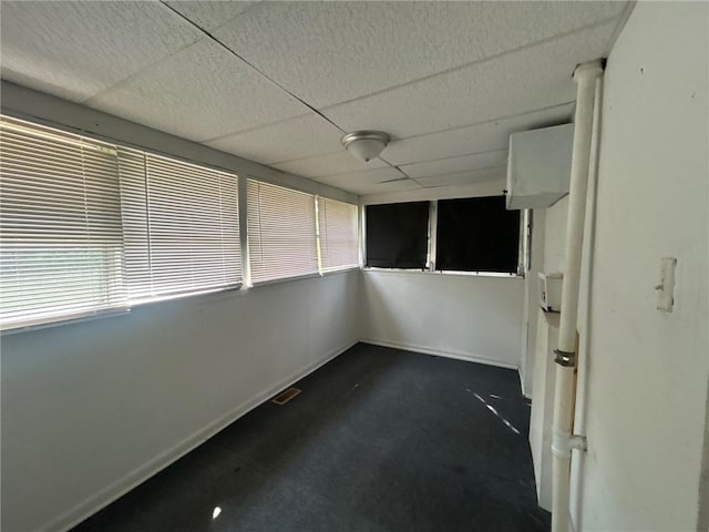 spare room with dark carpet, a drop ceiling, visible vents, and a wealth of natural light