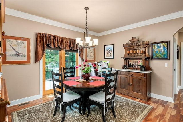 14029 Azalea Dr, Seneca, SC 29678 - dining space with ornamental molding, light wood finished floors, arched walkways, and a notable chandelier