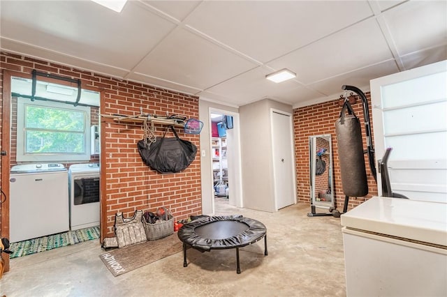 clothes washing area with brick wall, independent washer and dryer, and laundry area
