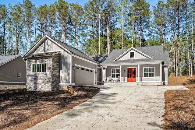 view of front of property featuring an attached garage, stone siding, covered porch, board and batten siding, and driveway