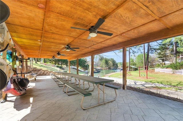 view of patio with a water view, fence, and a ceiling fan