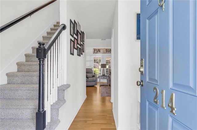 foyer entrance featuring french doors, light wood-style flooring, baseboards, and stairs