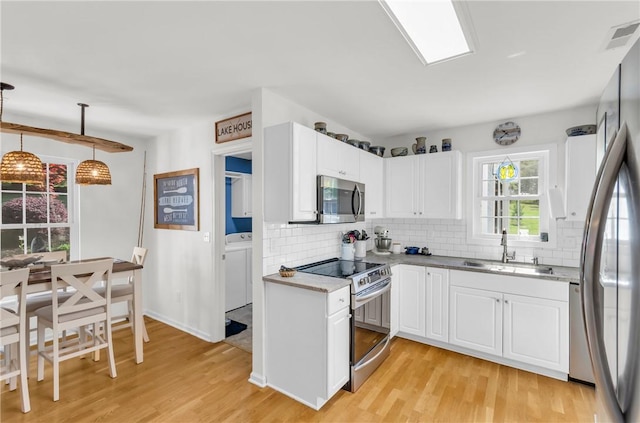 kitchen featuring a sink, light wood-style flooring, tasteful backsplash, and stainless steel appliances