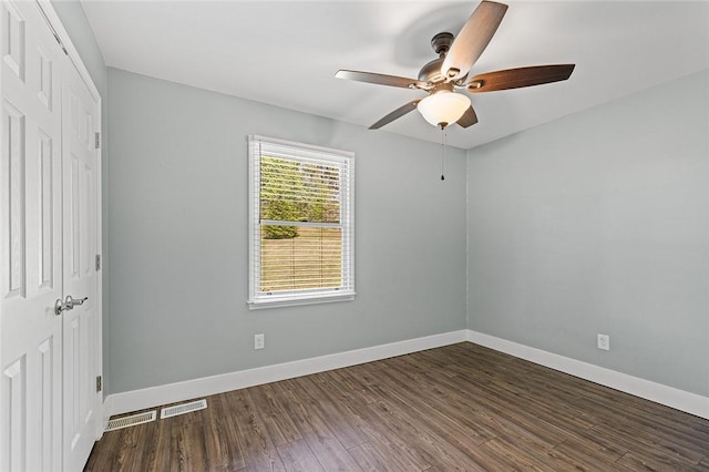 unfurnished bedroom with dark wood finished floors, visible vents, a closet, baseboards, and ceiling fan