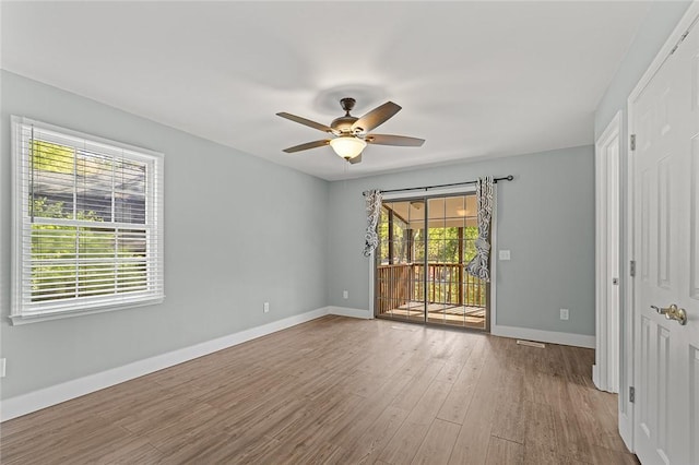 empty room featuring wood finished floors, baseboards, and ceiling fan
