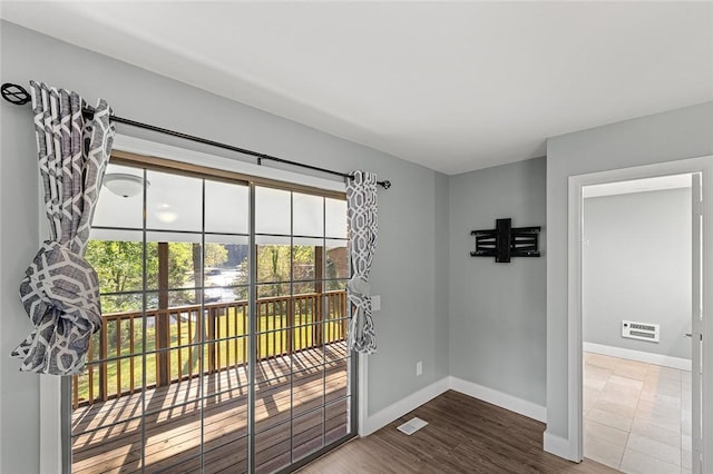 doorway with baseboards, wood finished floors, and visible vents