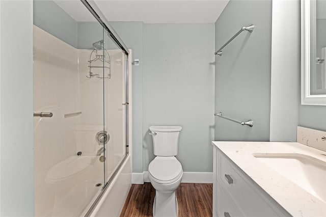 bathroom with bath / shower combo with glass door, toilet, baseboards, wood finished floors, and vanity