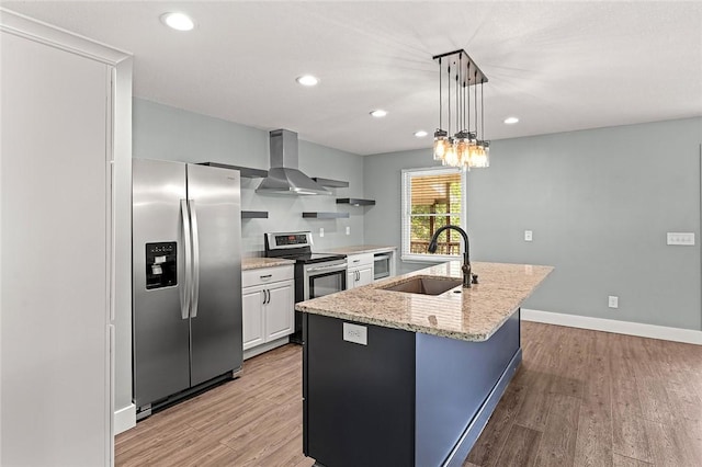kitchen featuring light wood-style flooring, a sink, appliances with stainless steel finishes, and wall chimney range hood