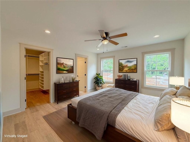 bedroom with light wood-style floors, recessed lighting, a walk in closet, baseboards, and a ceiling fan