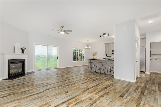 101 Pin Oak Ct, Easley, SC 29642 - unfurnished living room featuring a glass covered fireplace, ceiling fan with notable chandelier, baseboards, light wood-type flooring, and visible vents