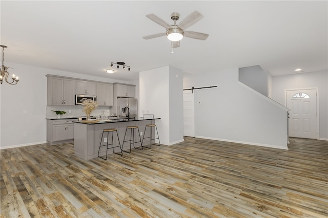 101 Pin Oak Ct, Easley, SC 29642 - kitchen with a breakfast bar area, appliances with stainless steel finishes, a barn door, gray cabinetry, and light wood finished floors