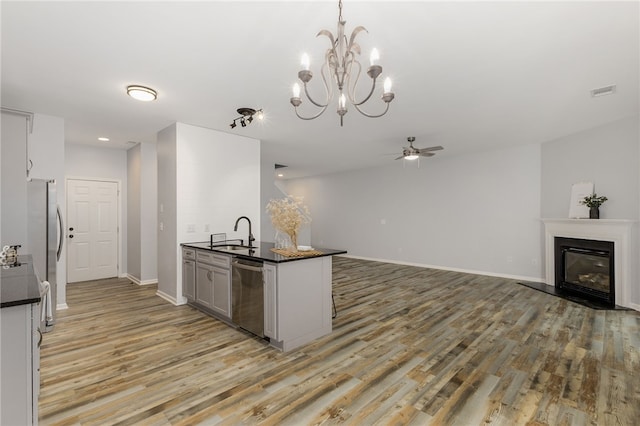 101 Pin Oak Ct, Easley, SC 29642 - kitchen with dark countertops, appliances with stainless steel finishes, a sink, ceiling fan with notable chandelier, and light wood finished floors