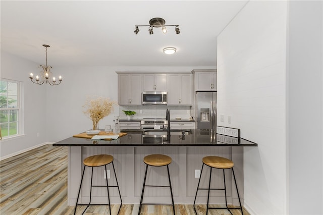101 Pin Oak Ct, Easley, SC 29642 - kitchen featuring gray cabinets, dark countertops, appliances with stainless steel finishes, an inviting chandelier, and a breakfast bar