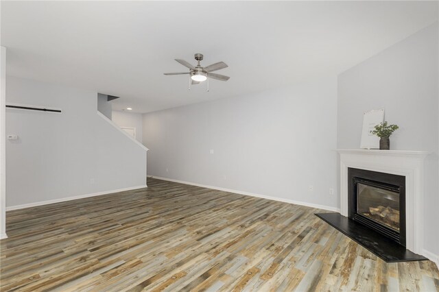 101 Pin Oak Ct, Easley, SC 29642 - unfurnished living room featuring stairs, a glass covered fireplace, wood finished floors, baseboards, and a ceiling fan