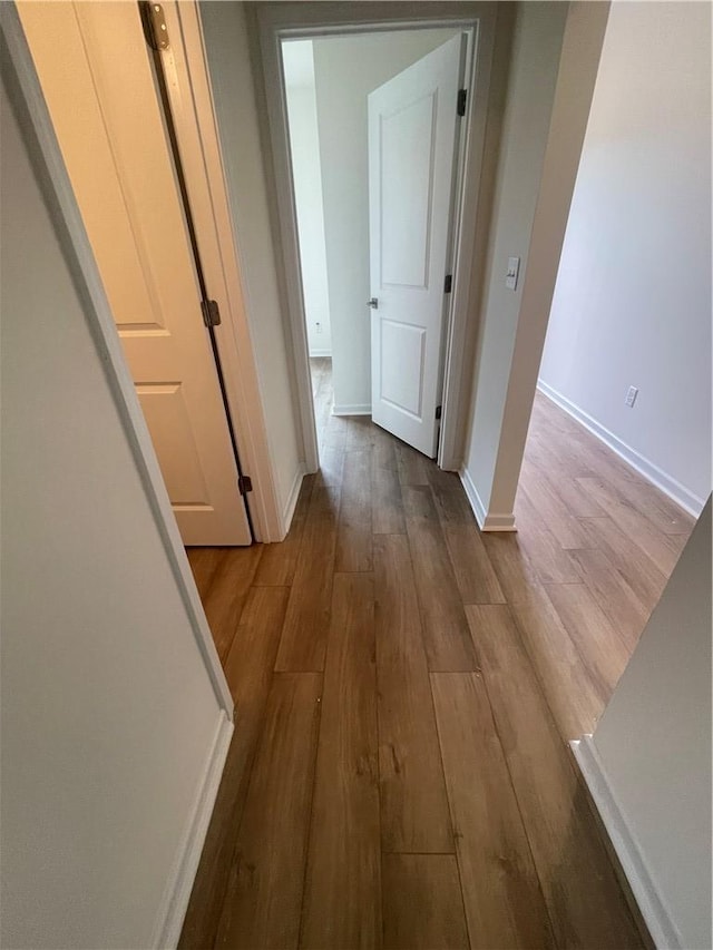 corridor featuring baseboards and wood finished floors