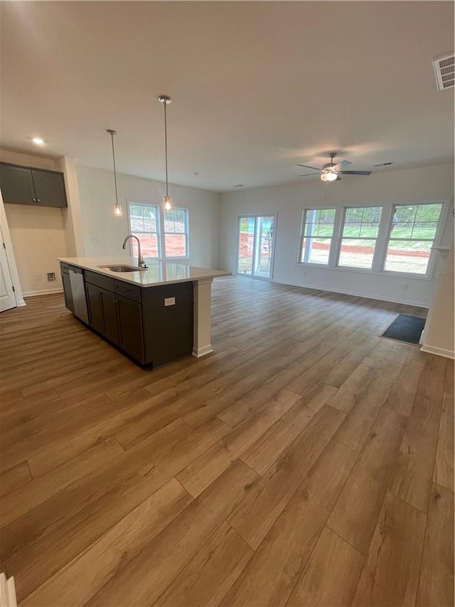 kitchen with a sink, open floor plan, visible vents, wood finished floors, and dishwasher