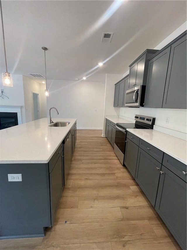 kitchen featuring a center island with sink, stainless steel appliances, visible vents, and a sink